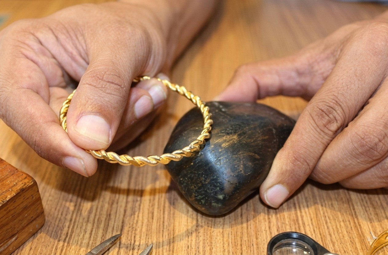 Gold jewellery being tested for purity using touchstone method during a doorstep valuation